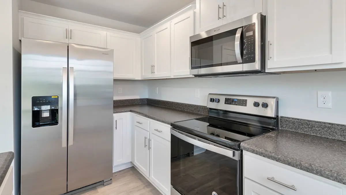 Cocina de una casa con refrigerador, microondas y estufa eléctrica de acero inoxidable